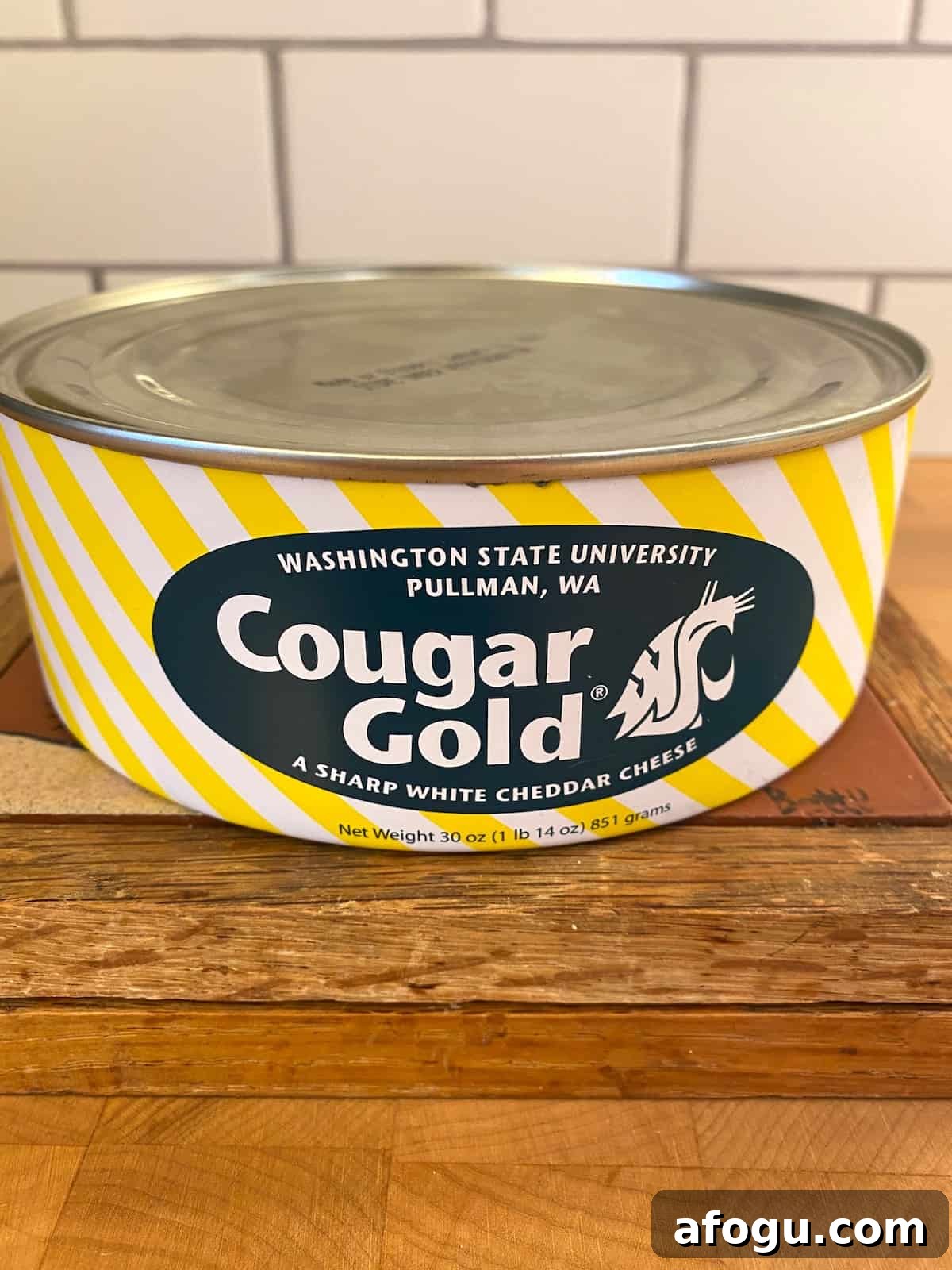 One can of cougar gold cheese on a cutting board.
